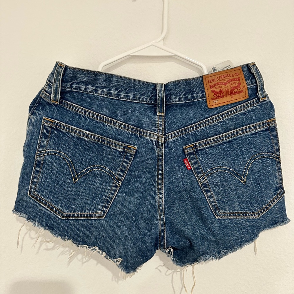 Blue denim High rise 501 Levi shorts with distressed ends. Size W25